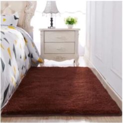 a brown rug next to a bed